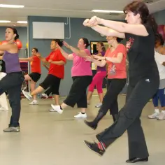 Grupa kobiet ćwiczy w rytm muzyki, wykonując energiczne ruchy. To właśnie zumba – świetna zabawa i trening w jednym!