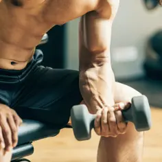 Mężczyzna ćwiczy biceps z hantlem, zastanawiając się, czy można ćwiczyć codziennie.
