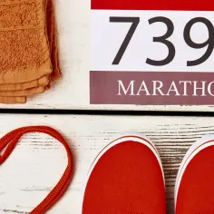 Pomarańczowy ręcznik, czerwone buty i tabliczka z napisem "MARATHON" i liczbą 7395. Czy to odległość w metrach, ile km ma maraton?